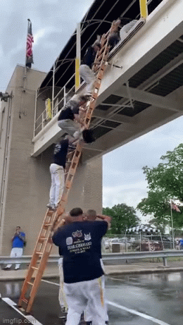 A group of firefighters coordinating together to pass along buckets of water to the top of a ladder